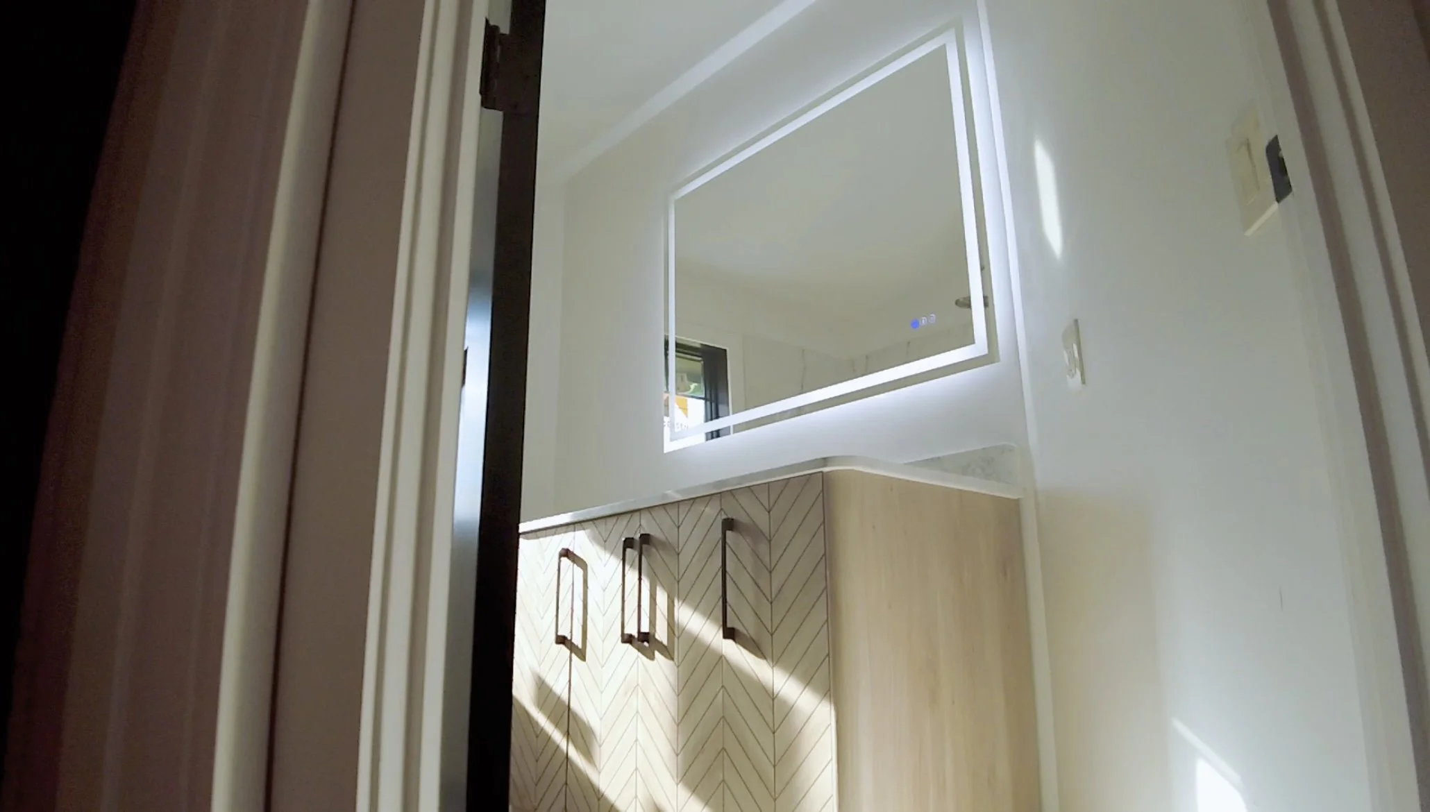 Finished bathroom vanity with illuminated mirror and custom cabinetry.